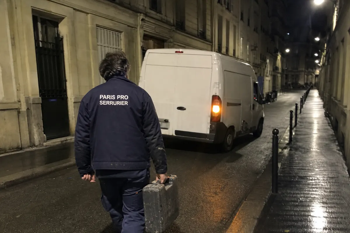 Serrurier rejoignant son véhicule d'intervention dans une rue de Paris la nuit